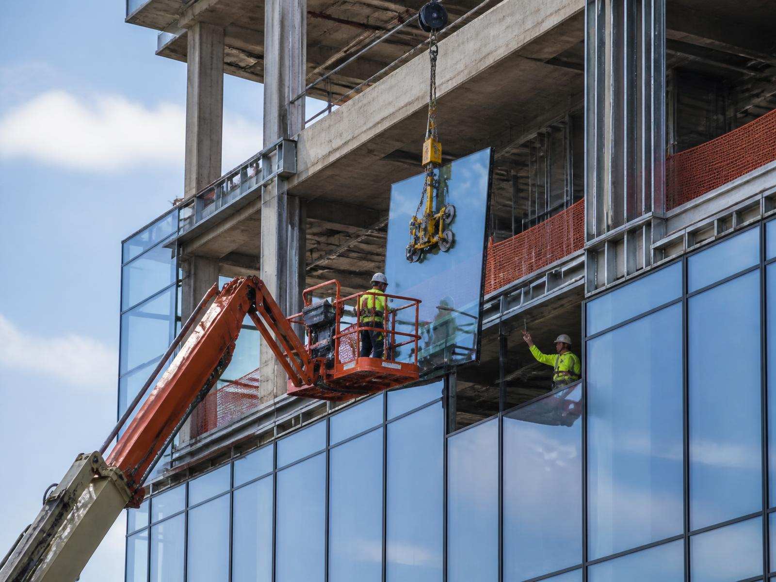 Glass curtain wall panel being set on a new commercial building under construction