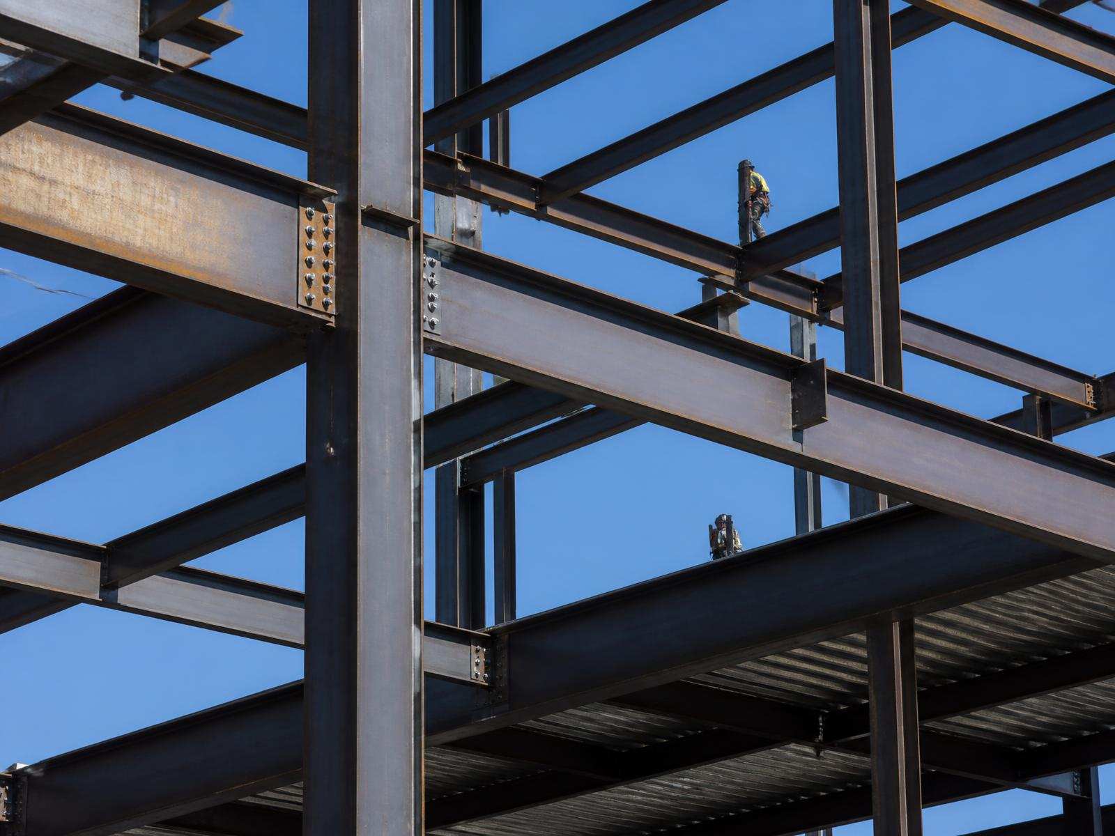Structural steel frame of a commercial building with ironworkers setting beams