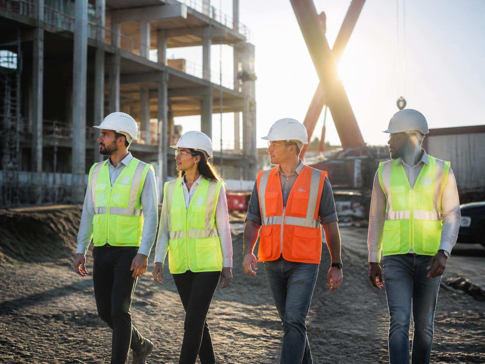Construction crew in hard hats and safety vests walking an active job site