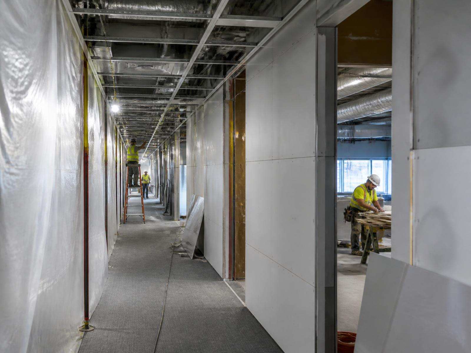 Interior commercial renovation in progress with temporary protection and exposed ceiling systems